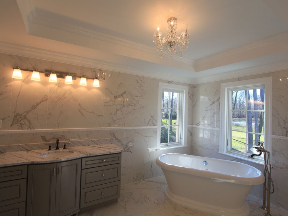 Finished bathroom with marble tile and chandelier lighting